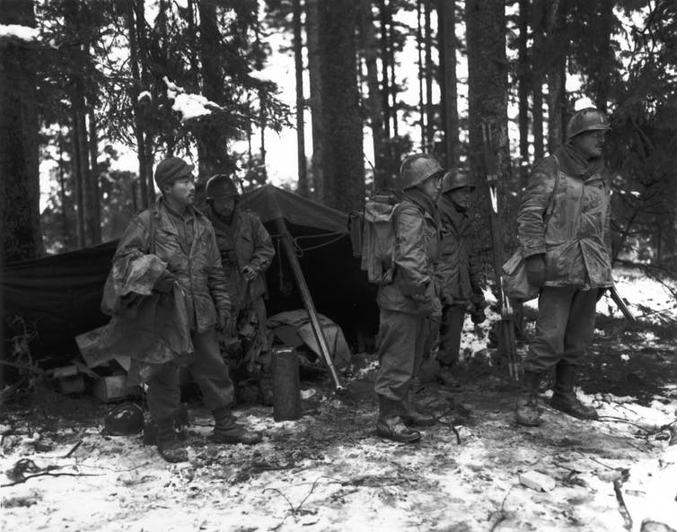 Japanese American soldiers stand in a French forest