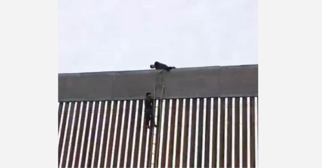 Three men quickly scale a newly built portion of the border wall