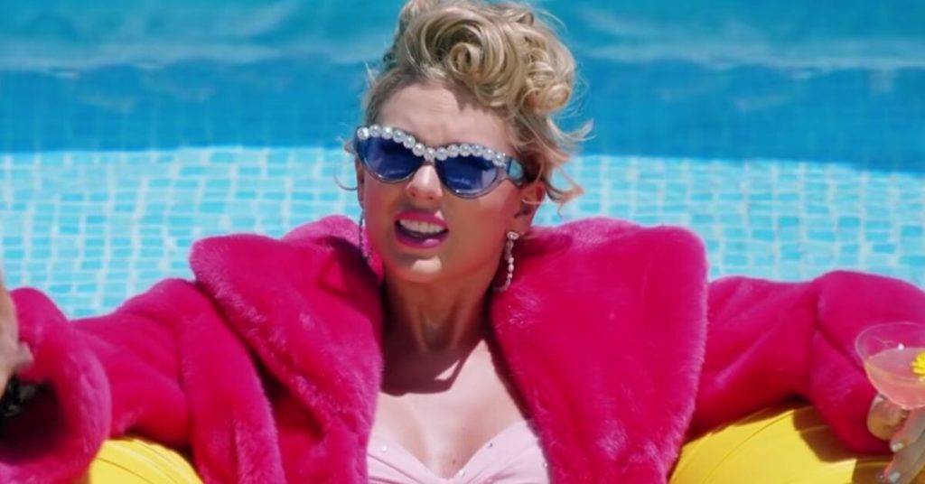 Taylor Swift in a pink jacket floating in the pool