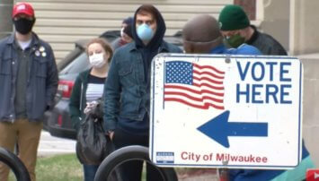 People standing in line to vote wearing face masks