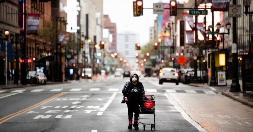 A person wearing a protective mask walks down Market Street in Philadelphia, Monday, April 13, 2020.