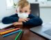 Child at a table wearing a facemask