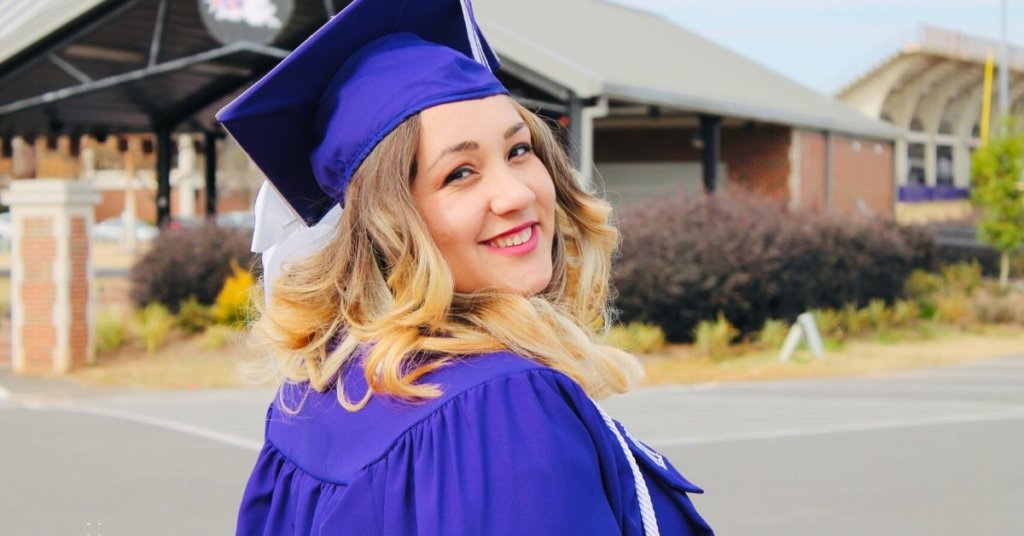 Woman in graduation cap and gown looking over her shoulder