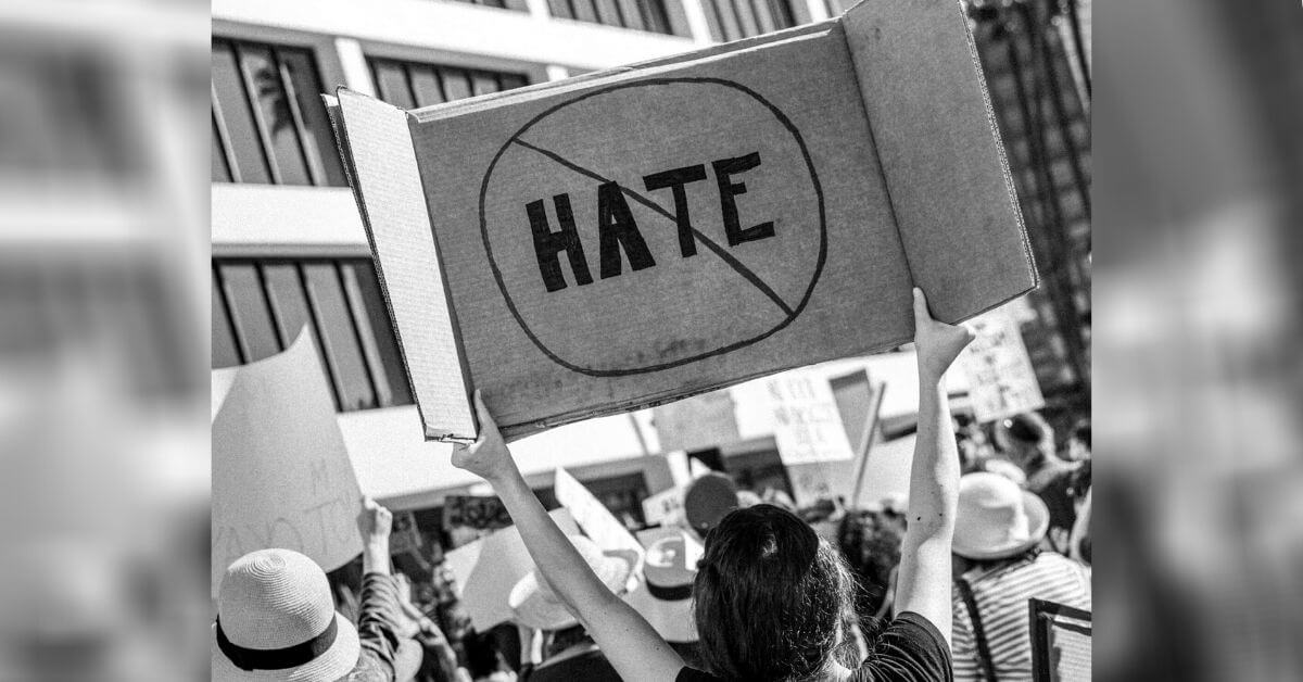 A photograph of protestors. One carries and anti-hate sign.
