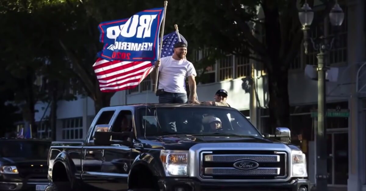 Person holding a Trump flag riding through Portland