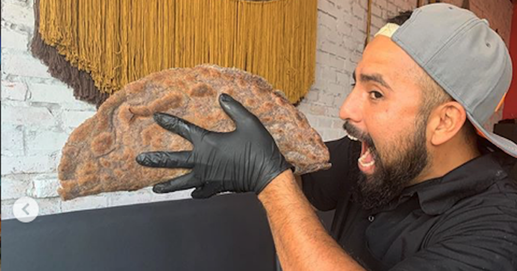 Charly Garcia bites into a giant vegan taco at Charly's Vegan Tacos.