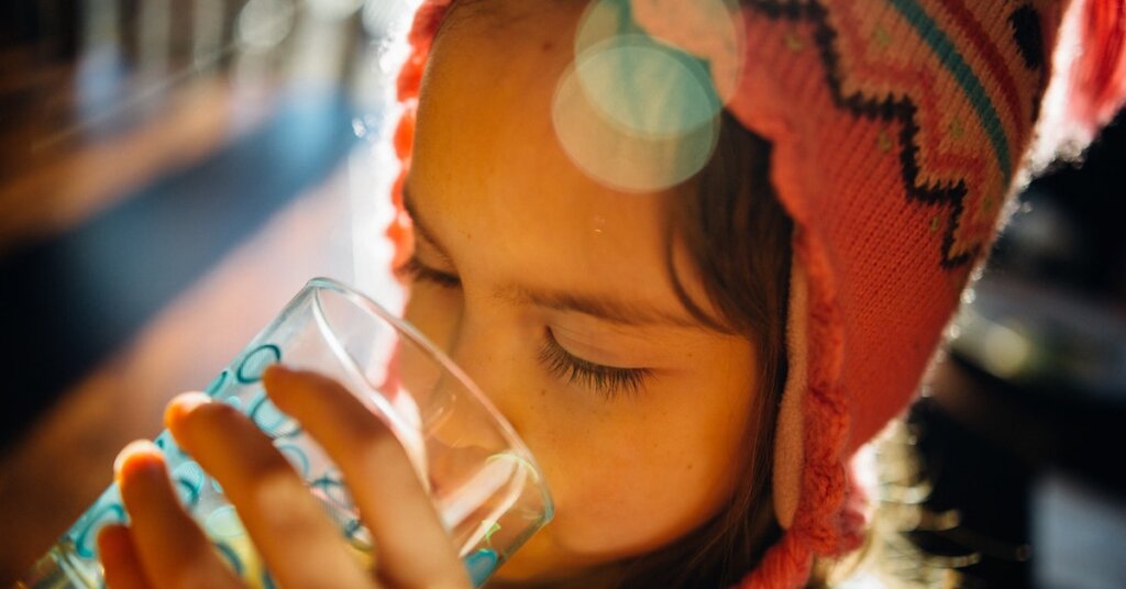 A child drinks from a water glass.