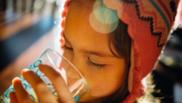 A child drinks from a water glass.