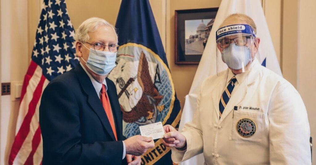 Mitch McConnell getting his COVID vaccine card from a doctor