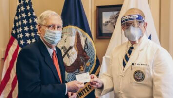 Mitch McConnell getting his COVID vaccine card from a doctor